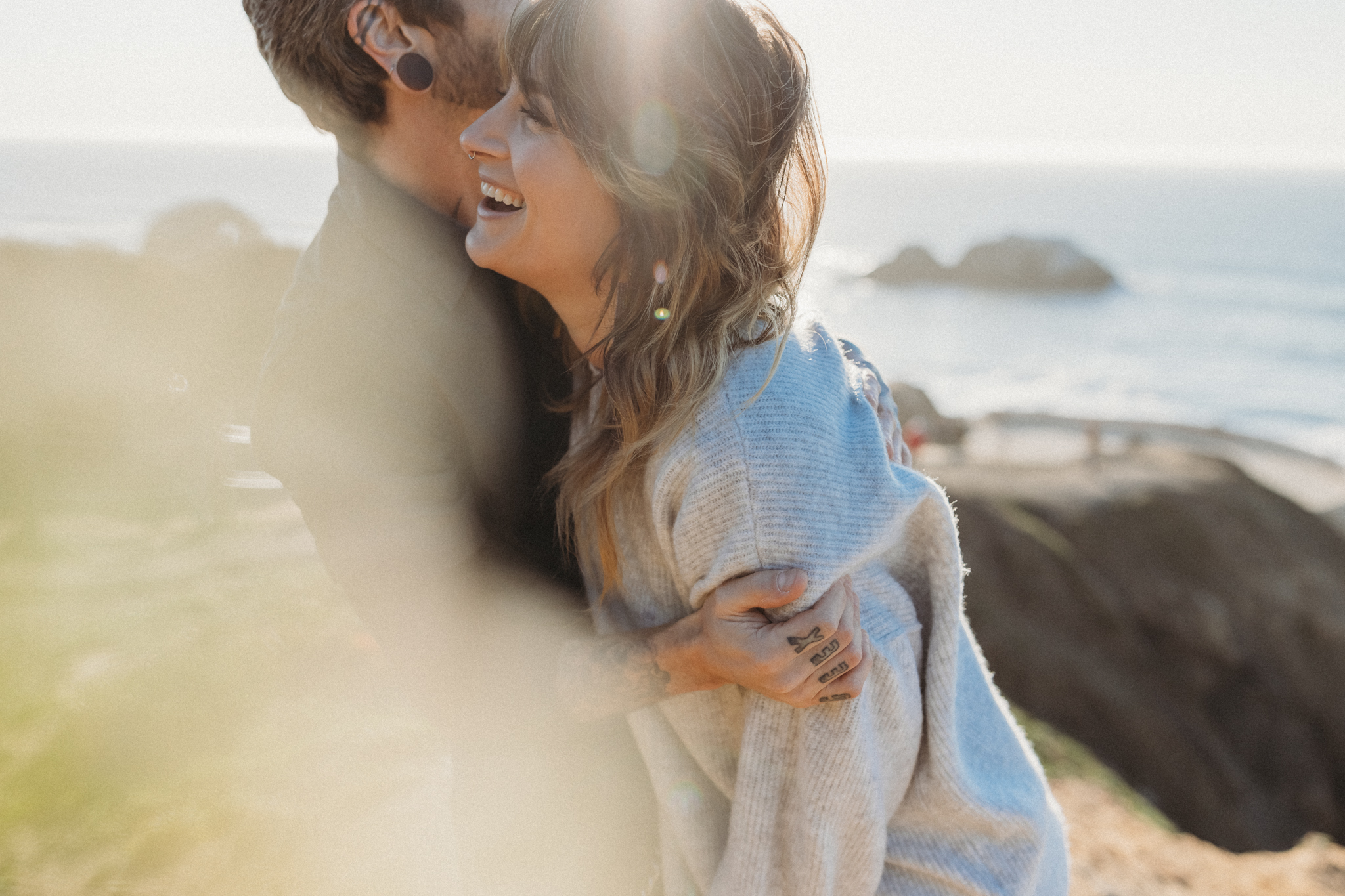 Couple laughing together at their outdoor engagement photos at Sutro Baths in San Francisco, California