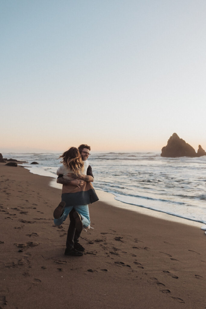 Couple spinning on the beach together at sunset at their engagement photo shoot at the Sutro Baths in San Francisco, California. Tips for feeling comfortable in front of the camera.