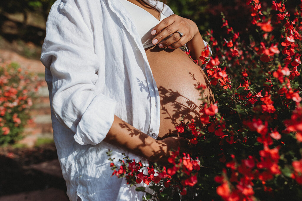 Pregnant woman's belly in lush flowers.