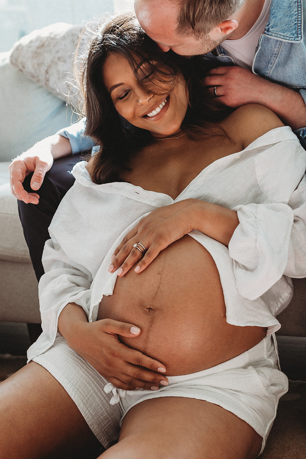 Expecting parents cuddling for in home maternity photos.