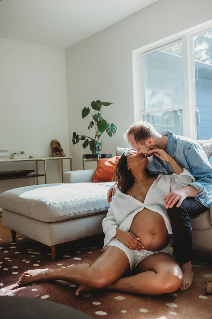 Expecting parents kissing in the living room for in home maternity photos.