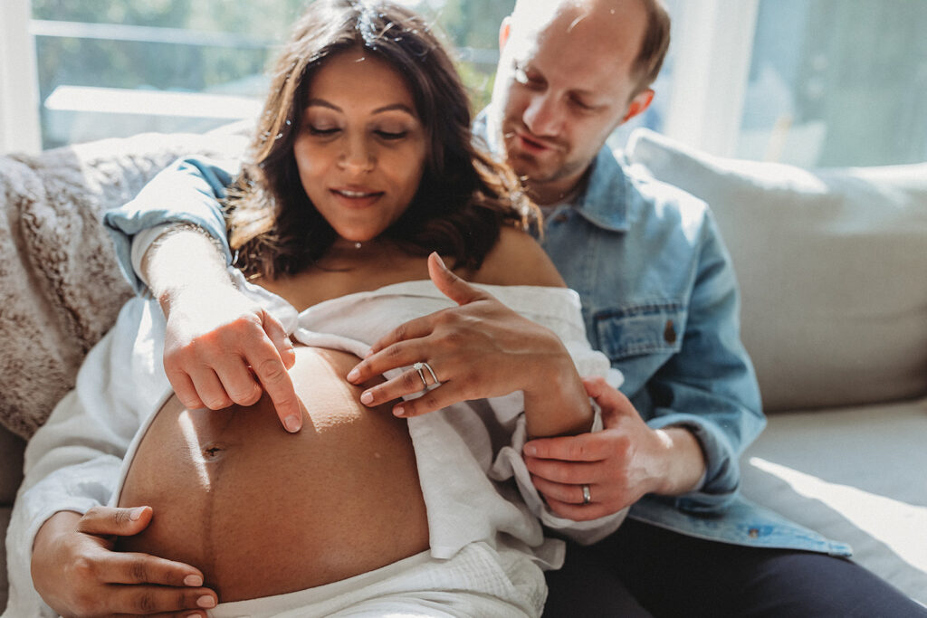 Expecting parents admiring mama's belly for in home maternity photos
