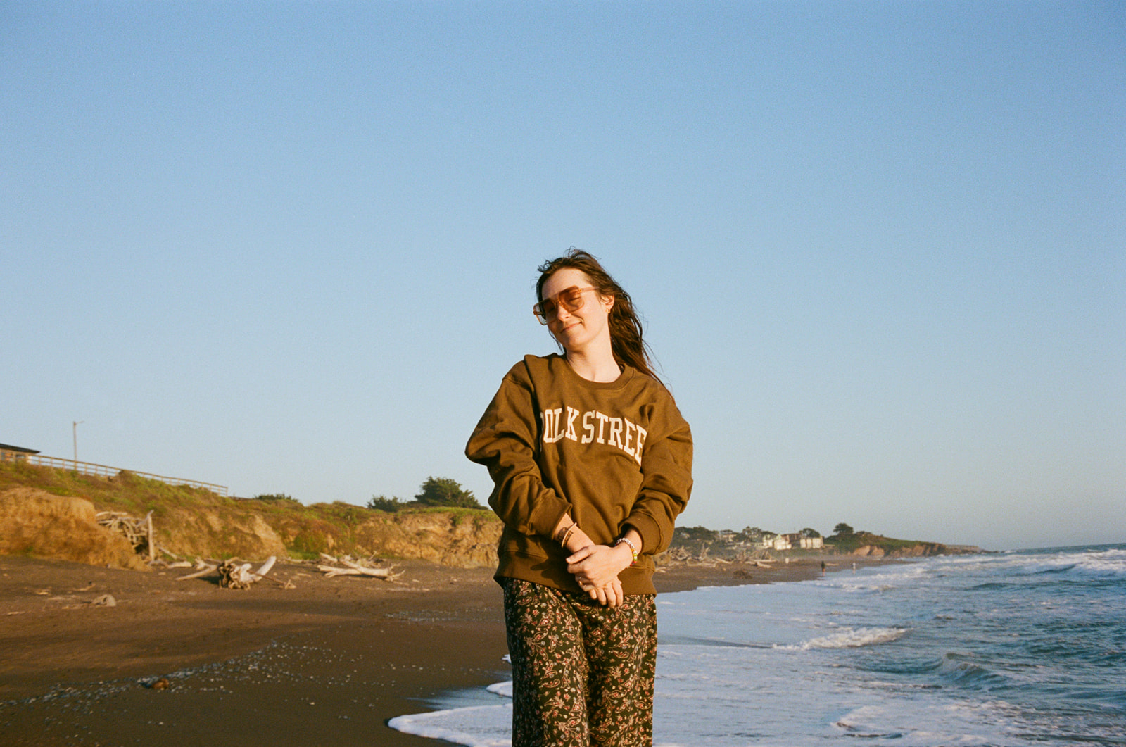 Girl standing and smiling at camera at sunset on Moonstone Beach in Cambria, California.
