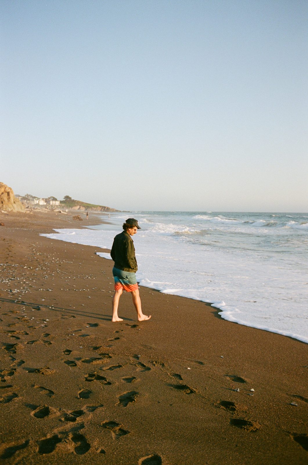 Man walking towards the ocean on Moonstone Beach at sunset in Cambria, California. Taken by Skyler Maire Photography.