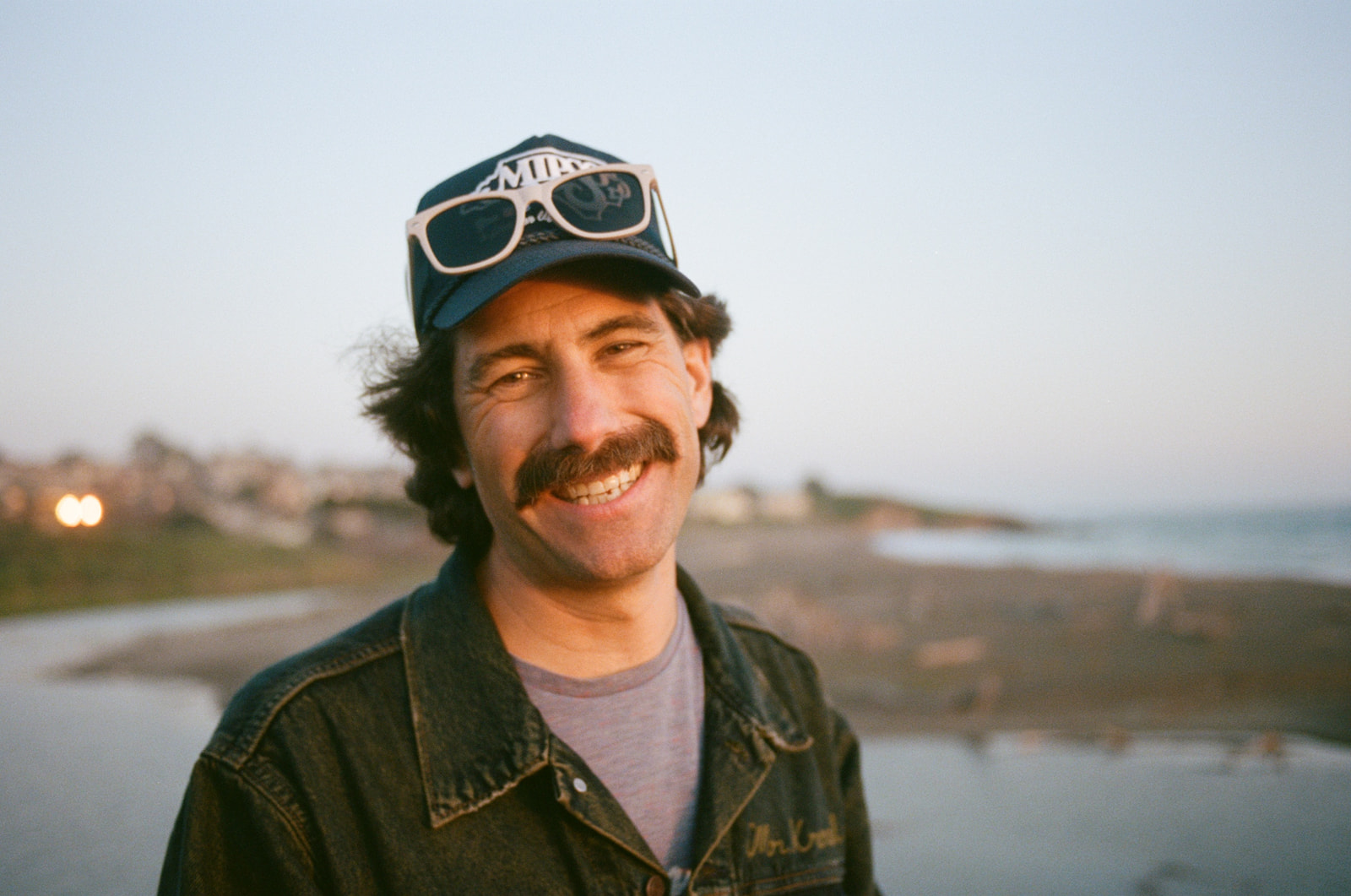 Close up of a handsome man smiling at the camera on Moonstone Beach in Cambria, California. Taken by Skyler Maire Photography. 