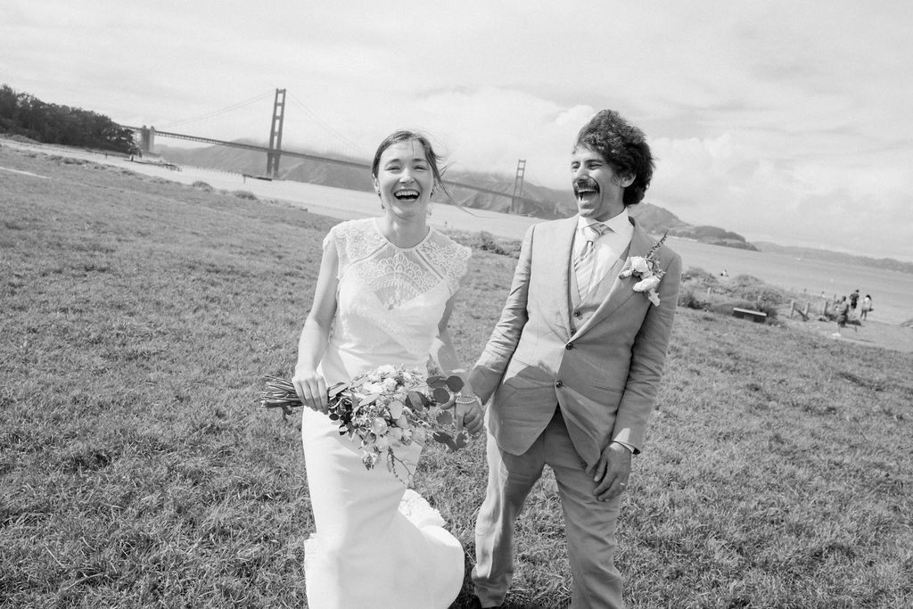 Joyful bride and groom walking across Crissy Field in San Francisco after their wedding ceremony.