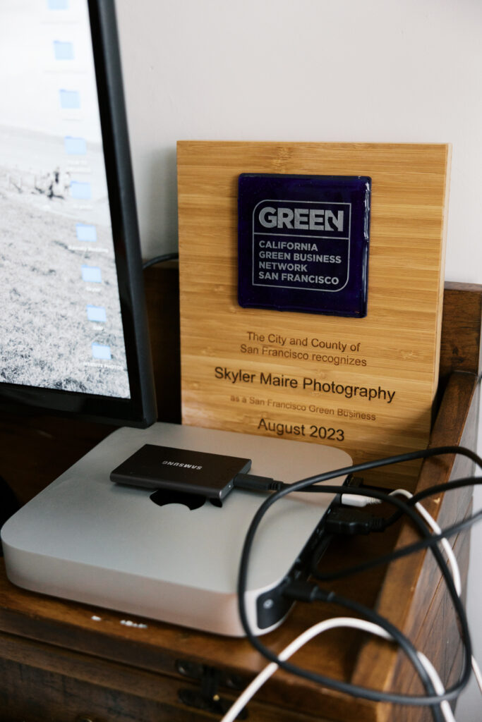 A mac mini, hard drive, and California Green Business award on a small home office desk.