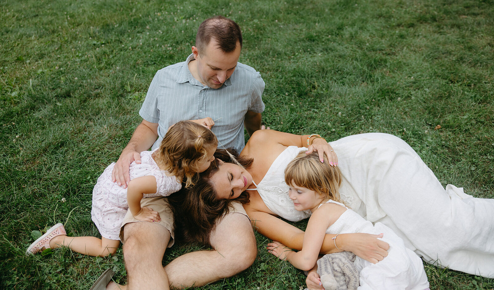 family of four cuddling on a grassy field in St. Paul, Minnesota.